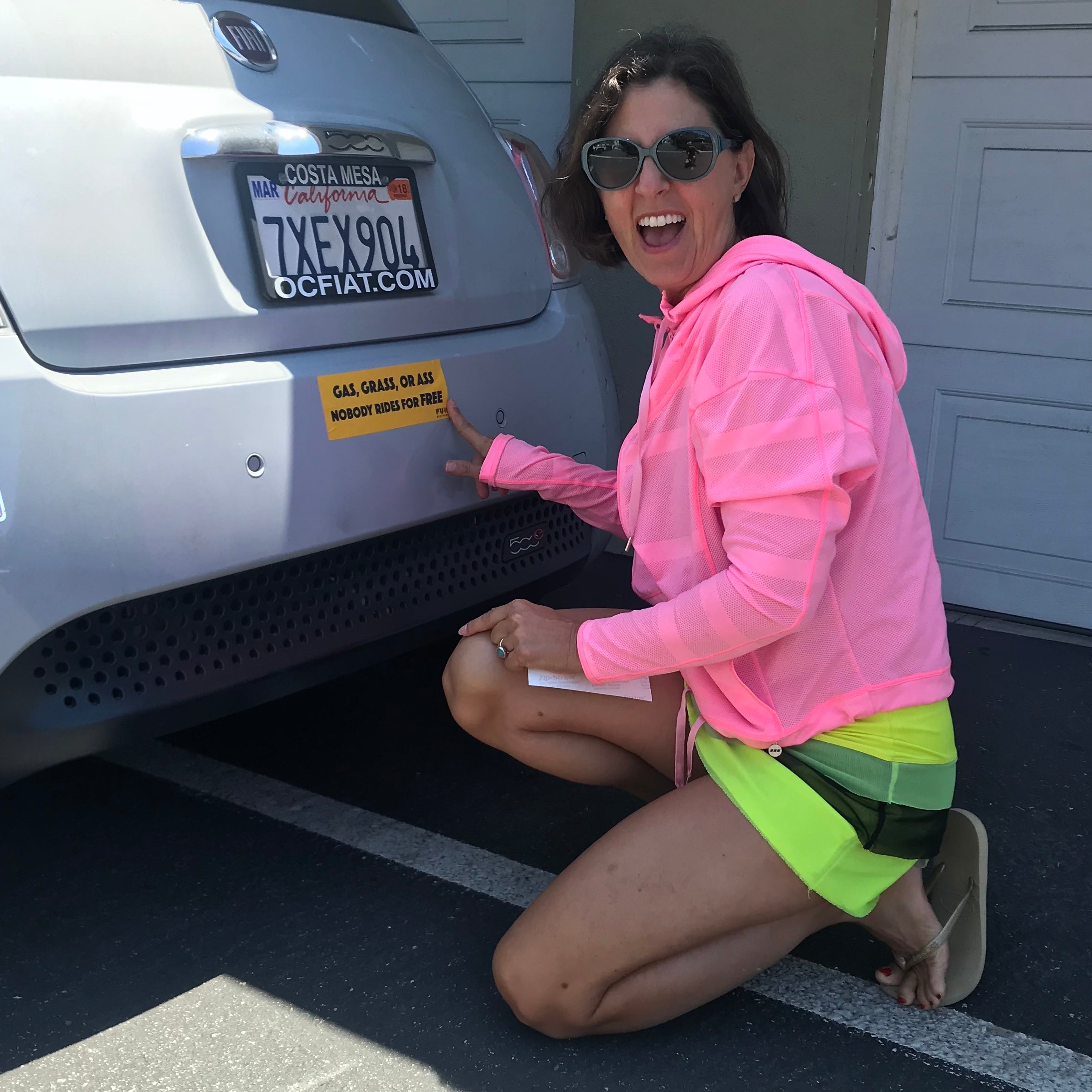 Woman applying prank bumper sticker to car